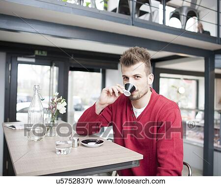 Stock Image - Portrait of young man drinking espresso in cafe. Fotosearch