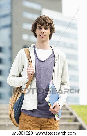 Portrait of young man standing at college campus View Large Photo Image Stock Image - Portrait of young man standing at college campus. Fotosearch