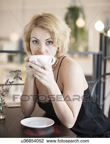 Portrait of young woman having coffee at restaurant table View Large Photo Image Stock Image - Portrait of young woman having coffee at restaurant table. Fotosearch