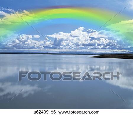 Stock Photograph - Rainbow over calm lake. Fotosearch