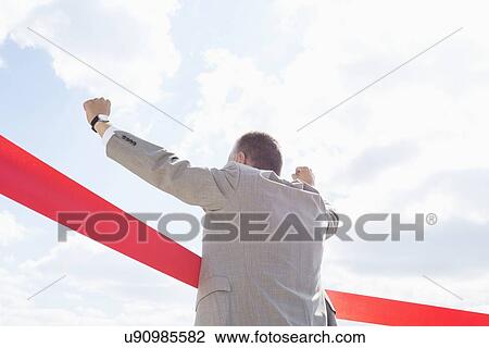 Rear view of businessman crossing finish line against sky View Large Photo Image Stock Image - Rear view of businessman crossing finish line against sky. Fotosearch