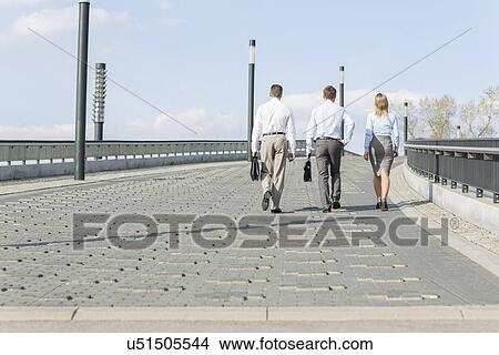 Rear view of businesspeople walking on bridge View Large Photo Image Picture - Rear view of businesspeople walking on bridge. Fotosearch