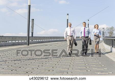 Rear view of businesspeople walking on bridge View Large Photo Image Stock Image - Rear view of businesspeople walking on bridge. Fotosearch