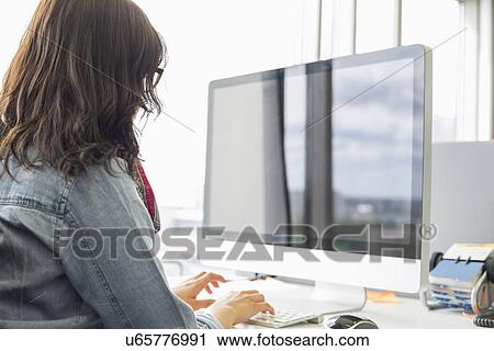 Rear view of businesswoman using desktop computer in creative office View Large Photo Image Stock Image - Rear view of businesswoman using desktop computer in creative office. Fotosearch