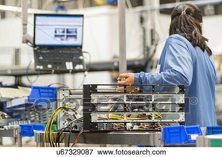 Stock Photo - Rear view of female technician repairing computer part in electronics industry. Fotosearch