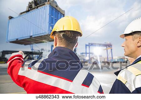 Rear view of male workers discussing in shipping yard View Large Photo Image Stock Image - Rear view of male workers discussing in shipping yard. Fotosearch