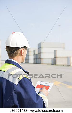 Rear view of middle-aged worker with clipboard in shipping yard View Large Photo Image Stock Image - Rear view of middle-aged worker with clipboard in shipping yard. Fotosearch