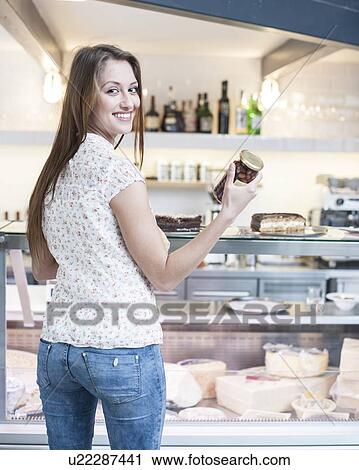 Rear view of smiling woman holding chocolate jar in front of display cabinet at cafe View Large Photo Image Stock Image - Rear view of smiling woman holding chocolate jar in front of display cabinet at cafe. Fotosearch