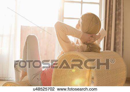 Stock Image - Rear view of woman relaxing on chair at home. Fotosearch