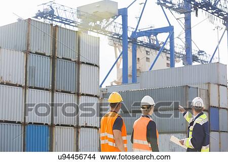 Rear view of workers inspecting cargo containers in shipping yard View Large Photo Image Picture - Rear view of workers inspecting cargo containers in shipping yard. Fotosearch