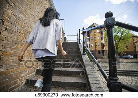 Rear view of young woman walking up stairs outdoors View Large Photo Image Stock Image - Rear view of young woman walking up stairs outdoors. Fotosearch