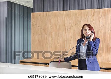 Receptionist talking on telephone in office View Large Photo Image Stock Photo - Receptionist talking on telephone in office. Fotosearch