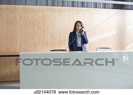 Receptionist talking on telephone in office View Large Photo Image Stock Photo - Receptionist talking on telephone in office. Fotosearch