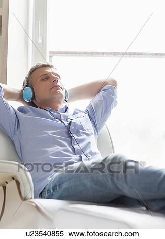 Stock Photography - Relaxed Middle-aged man listening to music at home. Fotosearch