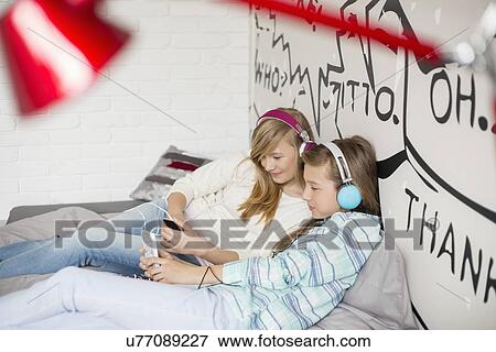 Relaxed sisters listening to music at home View Large Photo Image Stock Photo - Relaxed sisters listening to music at home. Fotosearch