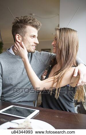 Stock Image - Romantic young couple looking at each other in cafe. Fotosearch