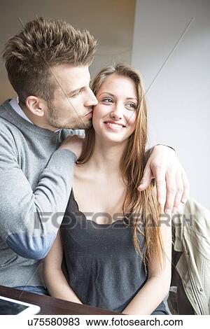 Stock Image - Romantic young man kissing woman in cafe. Fotosearch