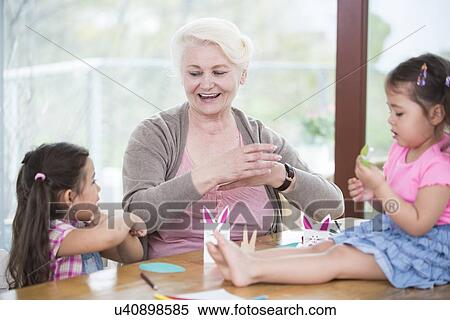 Senior woman assisting granddaughters in art work at home View Large Photo Image Stock Photography - Senior woman assisting granddaughters in art work at home. Fotosearch