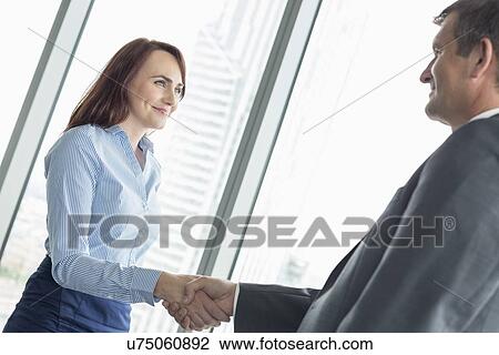Side view of business people shaking hands in office View Large Photo Image Stock Image - Side view of business people shaking hands in office. Fotosearch