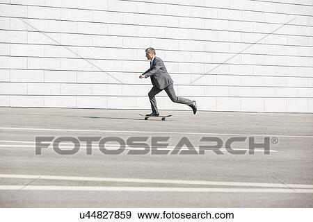 Side view of businessman skateboarding on street View Large Photo Image Stock Photo - Side view of businessman skateboarding on street. Fotosearch