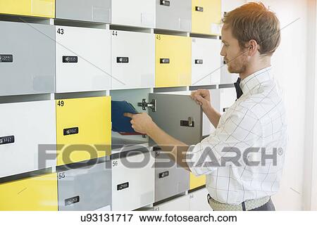 Side view of creative businessman putting files in locker at office View Large Photo Image Stock Photo - Side view of creative businessman putting files in locker at office. Fotosearch