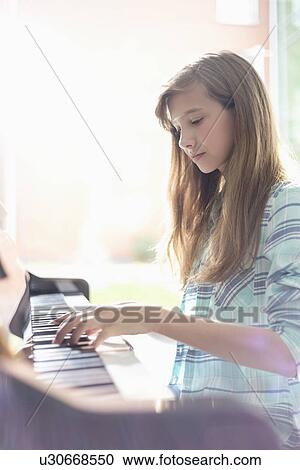 Side view of girl playing piano at home View Large Photo Image Stock Image - Side view of girl playing piano at home. Fotosearch