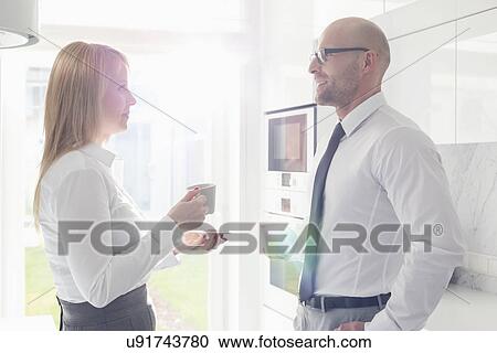 Side view of mid adult business couple talking at home View Large Photo Image Stock Image - Side view of mid adult business couple talking at home. Fotosearch