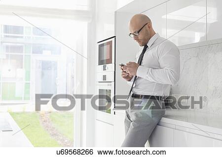 Side view of mid adult businessman using cell phone at home View Large Photo Image Stock Photograph - Side view of mid adult businessman using cell phone at home. Fotosearch