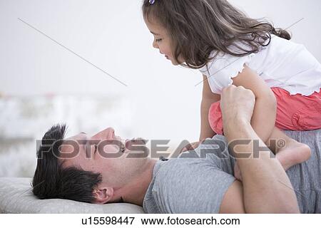Side view of playful father and daughter at home View Large Photo Image Stock Photo - Side view of playful father and daughter at home. Fotosearch