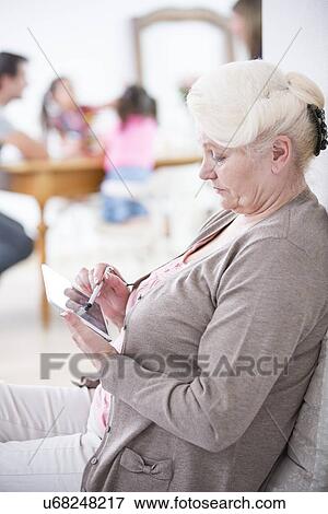 Side view of senior woman using digital tablet at home View Large Photo Image Stock Photo - Side view of senior woman using digital tablet at home. Fotosearch