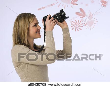Stock Photo - Side view of young woman photographing various patters over white background. Fotosearch