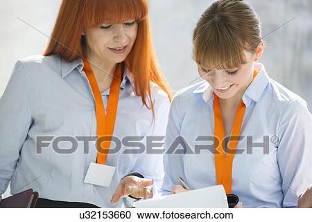 Smiling businesswomen discussing over documents in office View Large Photo Image Stock Image - Smiling businesswomen discussing over documents in office. Fotosearch