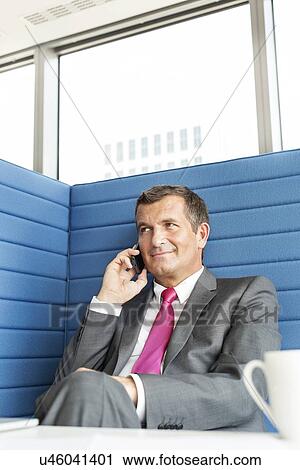 Smiling mature businessman talking on cell phone in office View Large Photo Image Stock Image - Smiling mature businessman talking on cell phone in office. Fotosearch