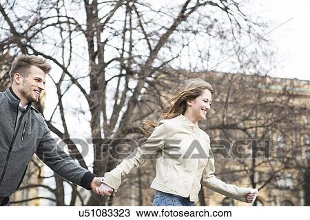 Smiling young man and woman holding hands and walking outdoors View Large Photo Image Stock Image - Smiling young man and woman holding hands and walking outdoors. Fotosearch