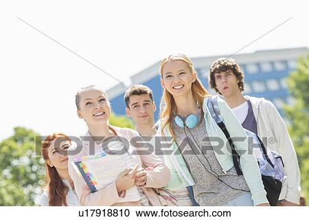 Stock Image - Smiling young students standing together at college campus. Fotosearch