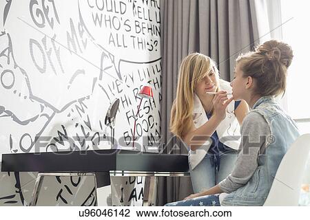 Teenage girl putting lipstick on sister at home View Large Photo Image Stock Image - Teenage girl putting lipstick on sister at home. Fotosearch