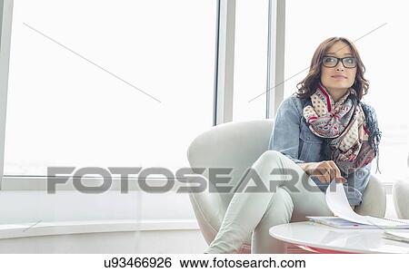 Thoughtful businesswoman sitting at table in creative office View Large Photo Image Stock Photograph - Thoughtful businesswoman sitting at table in creative office. Fotosearch