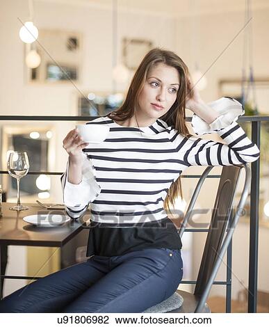 Thoughtful young woman looking away while having coffee at cafe View Large Photo Image Stock Image - Thoughtful young woman looking away while having coffee at cafe. Fotosearch