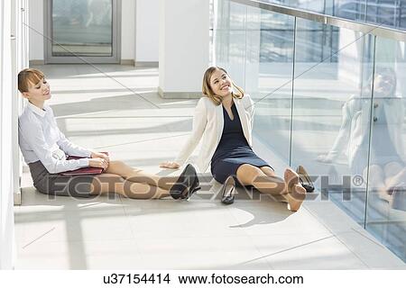 Tired businesswoman relaxing at office hallway View Large Photo Image Picture - Tired businesswoman relaxing at office hallway. Fotosearch