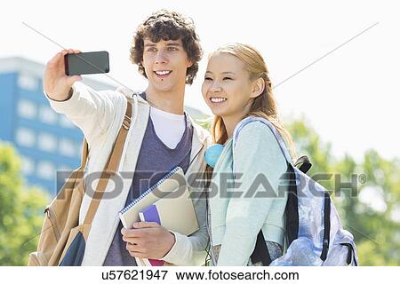Stock Photo - University friends taking selfie with smart phone at campus. Fotosearch