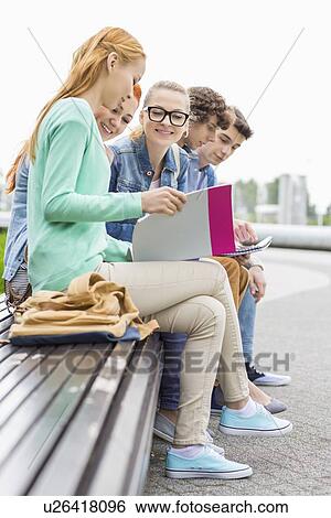 University students studying while sitting on low wall in park View Large Photo Image Stock Photograph - University students studying while sitting on low wall in park. Fotosearch