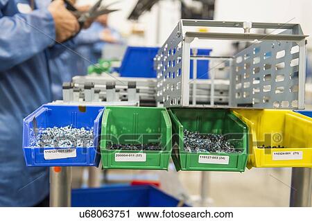 Stock Image - Variety of screws in tray with engineers working at electronics industry. Fotosearch