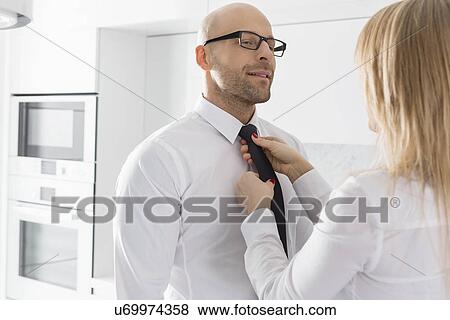 Woman adjusting businessman's tie at home View Large Photo Image Stock Photo - Woman adjusting businessman's tie at home. Fotosearch