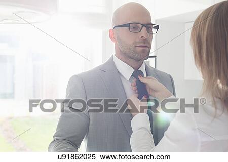 Woman adjusting businessman's tie at home View Large Photo Image Stock Photography - Woman adjusting businessman's tie at home. Fotosearch