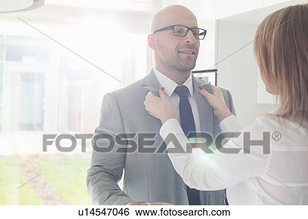 Woman dressing up businessman at home View Large Photo Image Stock Photograph - Woman dressing up businessman at home. Fotosearch