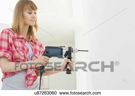 Woman drilling wall in new house View Large Photo Image Stock Image - Woman drilling wall in new house. Fotosearch