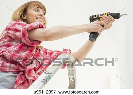 Woman drilling wall in new house View Large Photo Image Stock Photo - Woman drilling wall in new house. Fotosearch