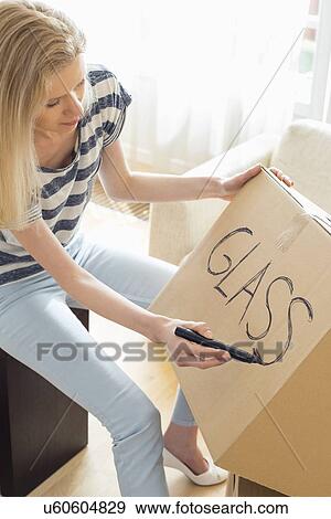 Woman labeling moving box with glass material at home View Large Photo Image Stock Photo - Woman labeling moving box with glass material at home. Fotosearch