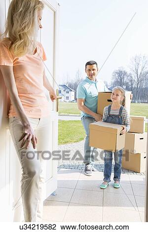 Woman looking at family with cardboard boxes entering new home View Large Photo Image Stock Image - Woman looking at family with cardboard boxes entering new home. Fotosearch