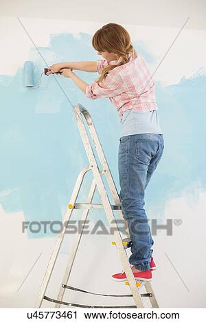 Woman on ladder painting wall with paint roller View Large Photo Image Stock Image - Woman on ladder painting wall with paint roller. Fotosearch